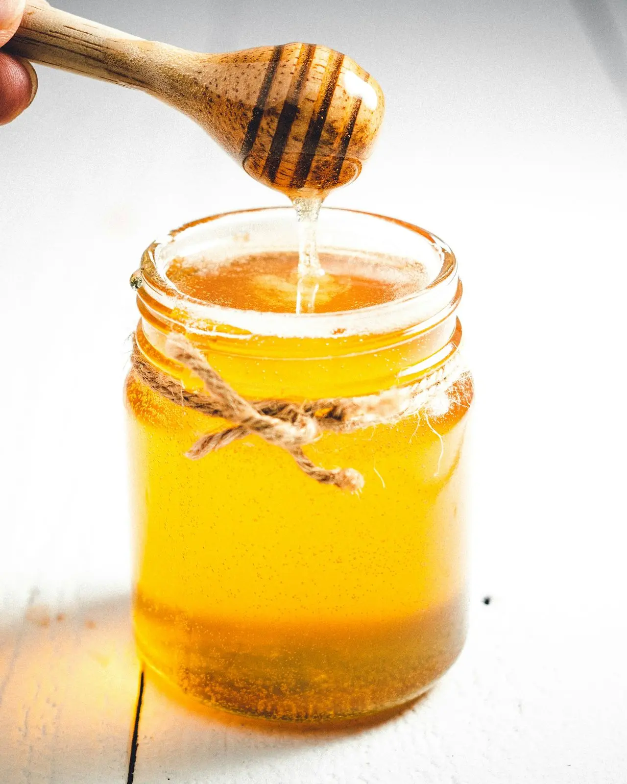 Honey dripping from a dipper into a jar
