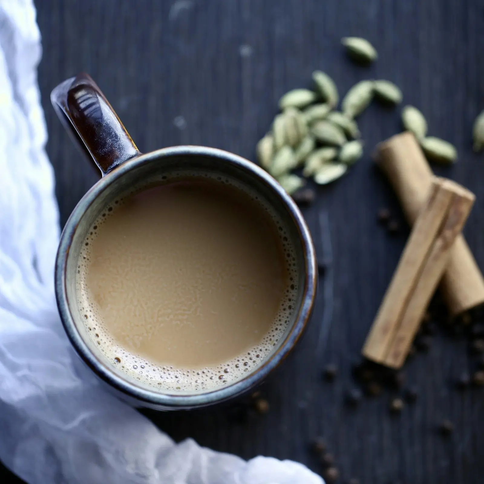 Mug of masala tea with green cardamom pods and cinnamon sticks